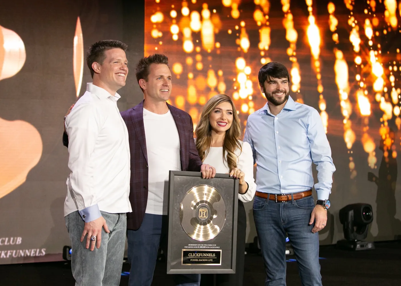 Stephanie and Bryan Dulaney holding a Two Comma Club award on stage