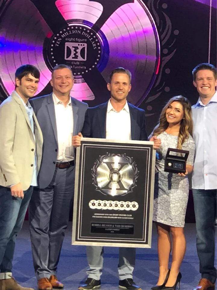 Stephanie and Bryan Dulaney on stage with a Two Comma Club X award