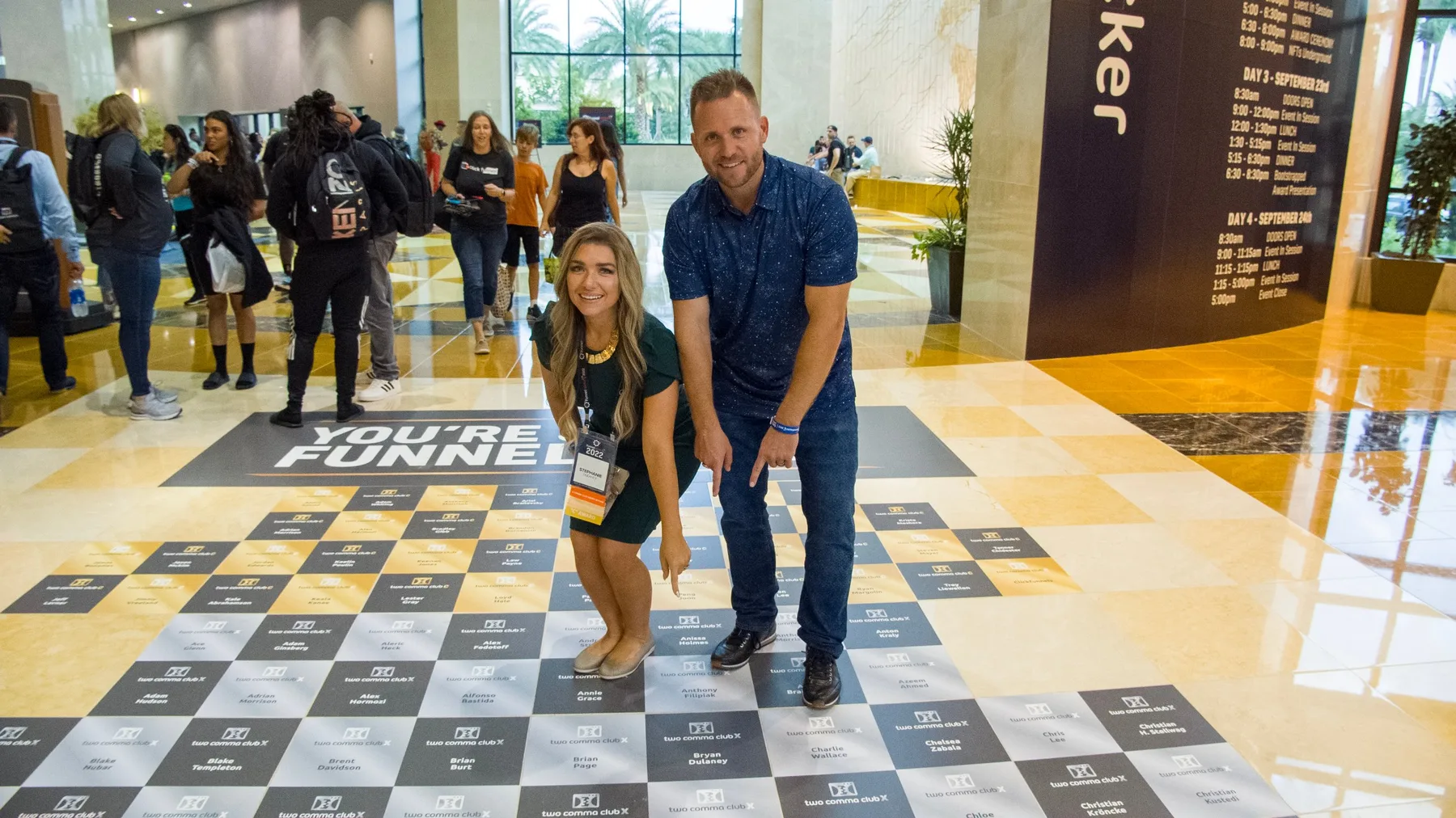 Stephanie and Bryan Dulaney pointing to their names among the Two Comma Club X winners on the floor at Funnel Hacking Live